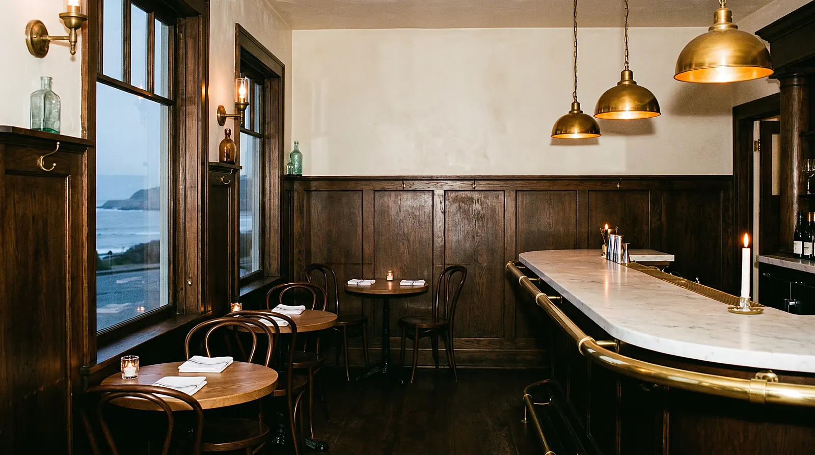 Tidemark's dining room at dusk, brass pendant lamps lit over the marble raw bar