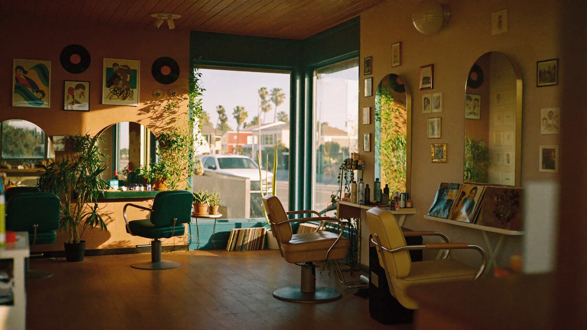Pleasure Head Salon — the plant-filled room at golden hour, vintage chairs and arched mirrors